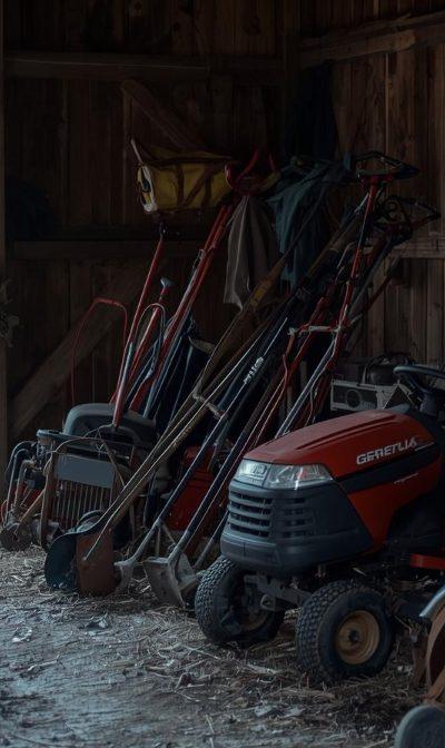 Lawn mower in garage being prepared for winter storage with fuel stabilizer and tools